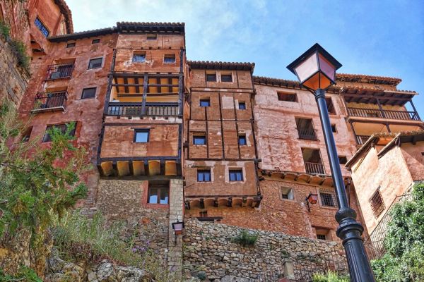 Albarracín encaramado sobre la Sierra de Albarracín, entre roca rojiza y pinar.