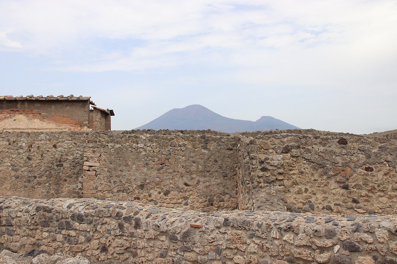 Calles empedradas de Pompeya con el Vesubio al fondo, lo primero que verás al llegar.